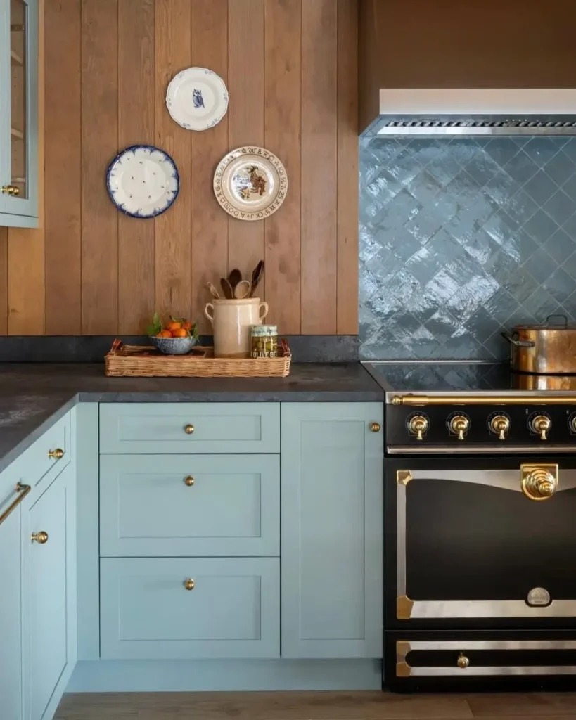 A modern rustic kitchen with light blue cabinets, a vertical wood panel backsplash, and a glossy blue tile accent behind the range.