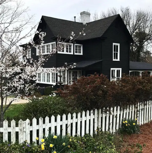 A classic black house with crisp white window trim and a matching white picket fence for a timeless, high-contrast look.