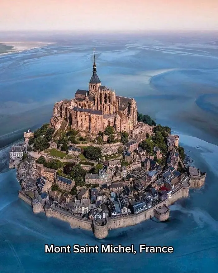 An architectural idea of a historic tiered community spiraling up a tidal island, topped by an abbey.