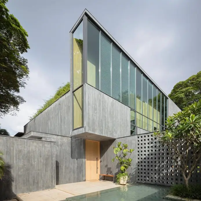 A contemporary concrete home with a dramatic triangular profile and a large glass facade.