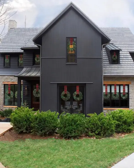 A sophisticated black house exterior that blends traditional fieldstone with modern vertical siding.