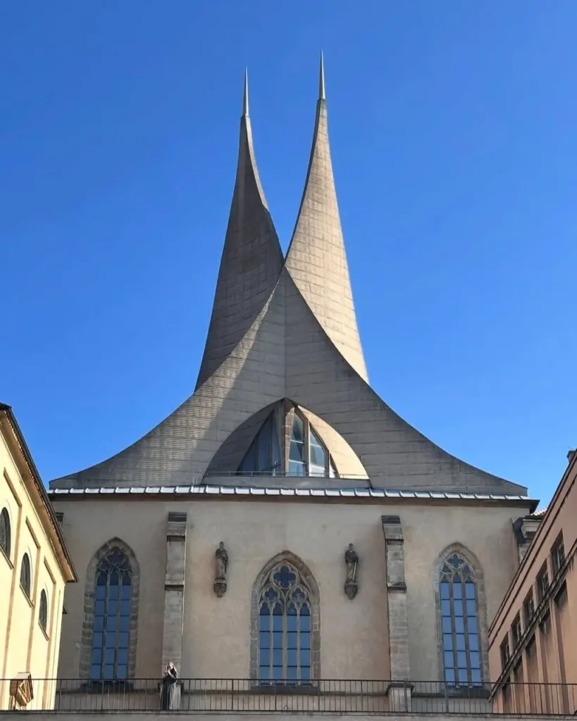 A unique building crowned with two dramatic, tent-like spires, a modern reinterpretation of a historic architectural idea.