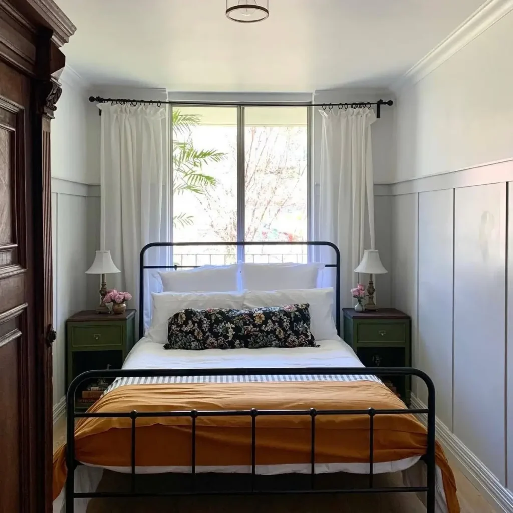 A cozy bedroom design with a black metal bed, matching green nightstands, and light gray board and batten walls creating a symmetrical look.