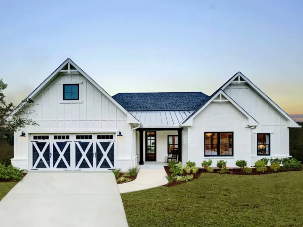 A modern off-white farmhouse with striking X-brace garage doors and black window frames.