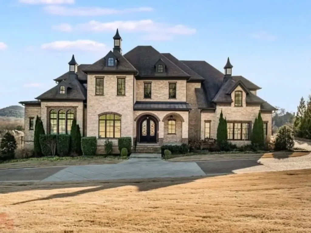 The Ultimate Guide to Luxury Mansion Design: 33 Ideas for Grandeur 31 A light brick mansion house with a dark roof and whimsical turret-like finials.