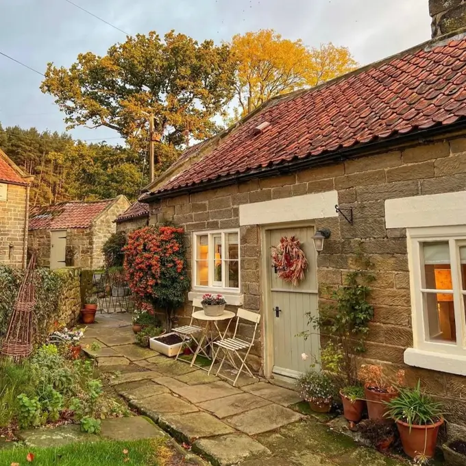 A cozy stone courtyard of an English country home with a small bistro set and potted plants.