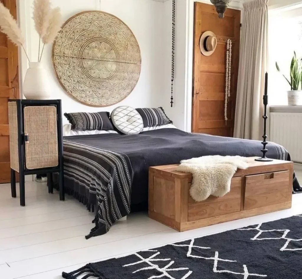A high-contrast boho bedroom with a large, round, carved wooden medallion hanging over a bed with black and white bedding.