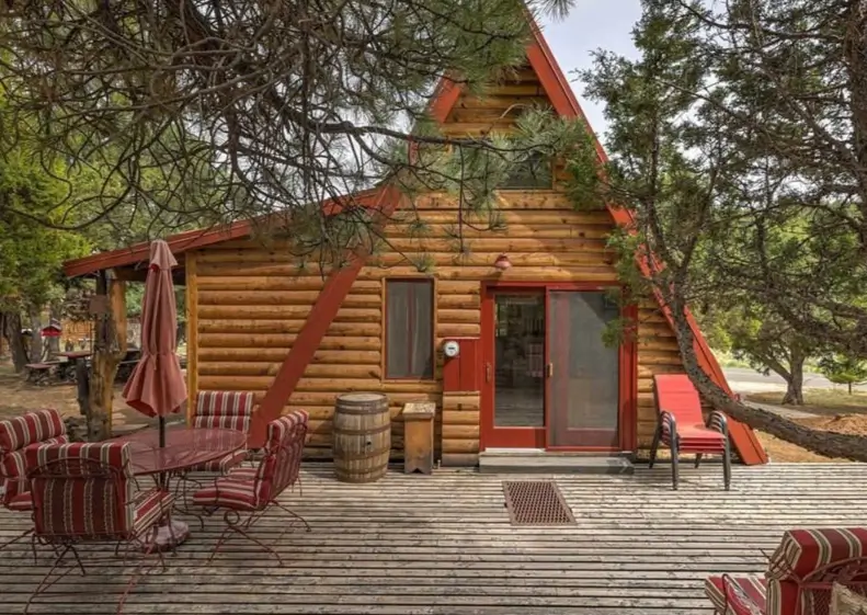 60 Charming Small Log Cabin Ideas to Inspire Your Rustic Retreat 31 An A-frame small log cabin home with red trim and a sliding glass door opening onto a spacious wooden deck.