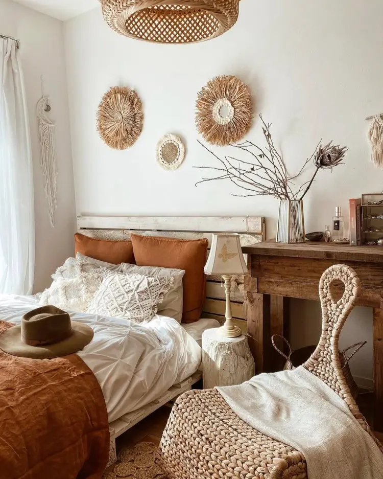 A neutral-toned boho bedroom with three round woven raffia wall hangings clustered above a rustic wooden headboard.
