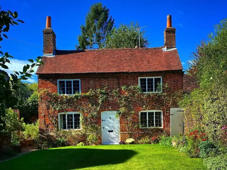 A symmetrical red brick British country house in the Georgian style with a white door and climbing ivy.