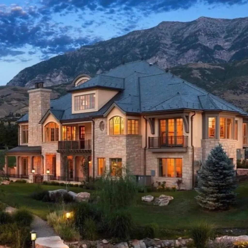 16 Mountain Mansions That Define Luxury Alpine Living 7 An elegant stone mountain estate with a classic slate roof and refined architectural lines, set against a backdrop of wild, rugged peaks.