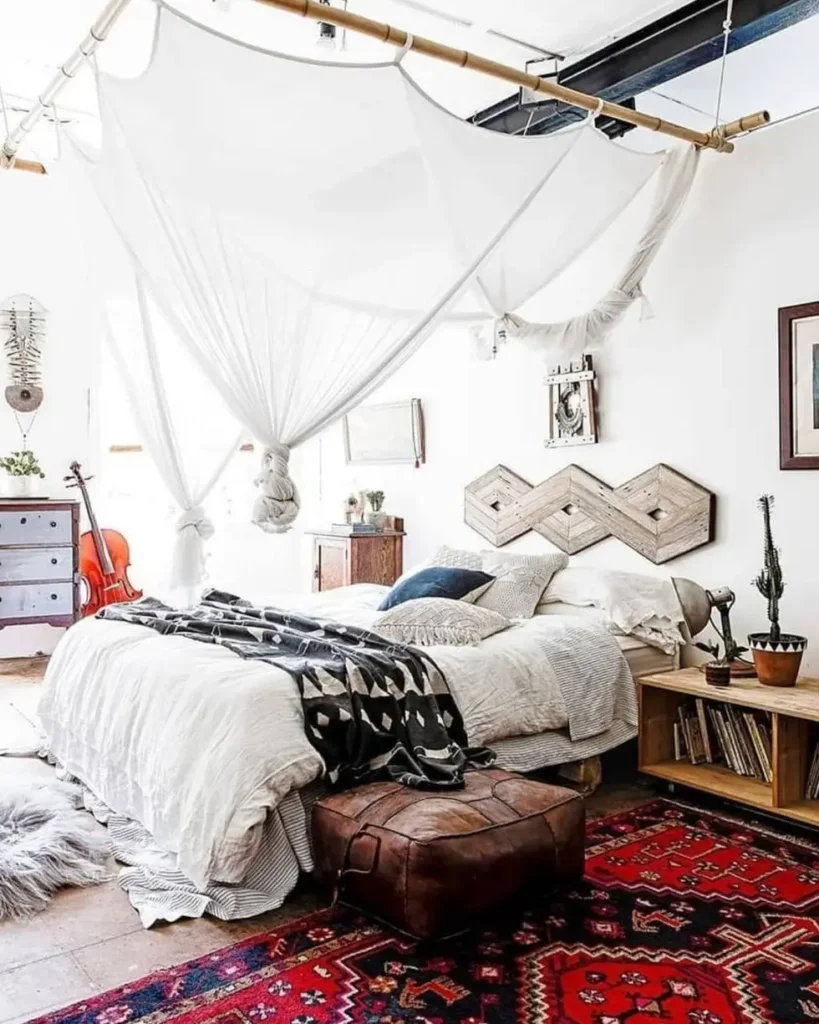 A boho bedroom with a geometric reclaimed wood headboard, a white fabric canopy, and a red patterned rug.