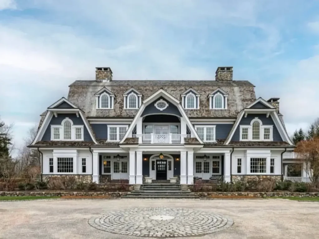 The Ultimate Guide to Luxury Mansion Design: 33 Ideas for Grandeur 35 A grand Shingle Style luxury mansion with a distinctive gambrel roof and blue siding.