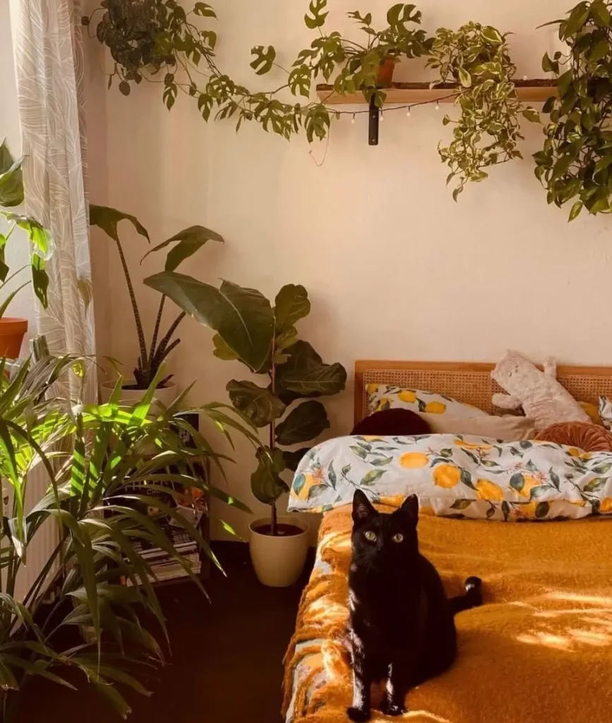 A sunlit bedroom with a bed featuring a bright lemon-print duvet and a warm yellow blanket, surrounded by plants.