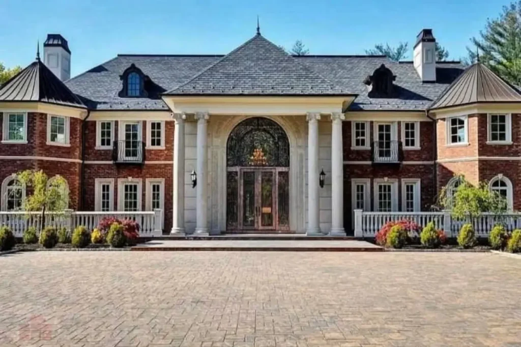The Ultimate Guide to Luxury Mansion Design: 33 Ideas for Grandeur 7 A red brick mansion featuring a grand stone portico with four large columns.