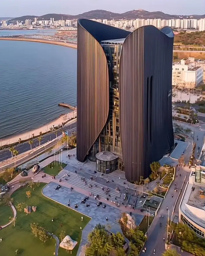 A tall, dark building with a flowing, sculptural facade that drapes like fabric, an inspiring architectural idea.