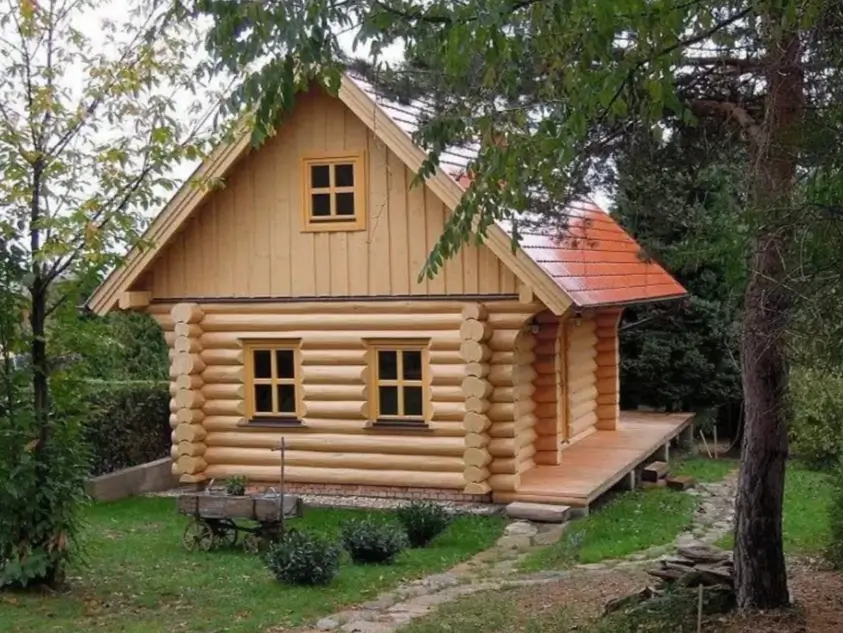 60 Charming Small Log Cabin Ideas to Inspire Your Rustic Retreat 6 A small log cabin design with rounded logs on the bottom, vertical siding on top, and a red tile roof.