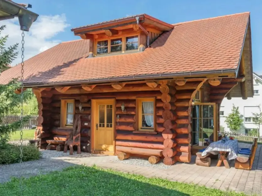 60 Charming Small Log Cabin Ideas to Inspire Your Rustic Retreat 42 A small log cabin home featuring a warm finish, a red tile roof, and a large dormer window.