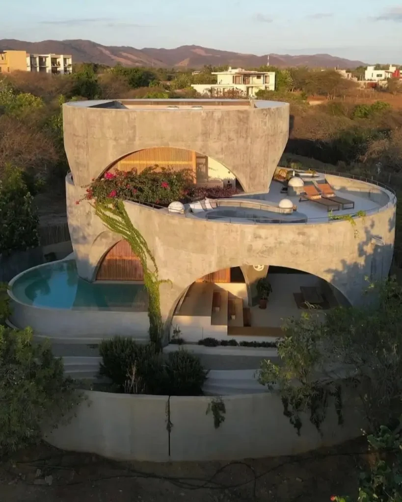 A stunning multi-level brutalist house defined by its sculptural curves, large arched openings, and a serene poolside terrace.