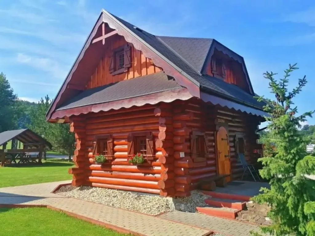 60 Charming Small Log Cabin Ideas to Inspire Your Rustic Retreat 53 A small log cabin with a reddish stain, dark shutters, and flower boxes under the windows.