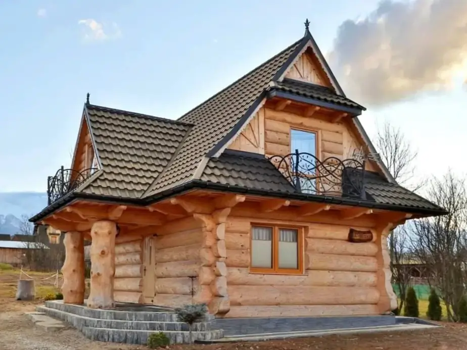 60 Charming Small Log Cabin Ideas to Inspire Your Rustic Retreat 55 A light-colored small log cabin with a tiled roof and two second-story balconies with decorative metal railings.