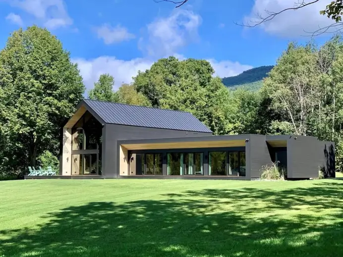 A modern black house exterior softened by the warm tones of natural wood soffits and recessed walls.
