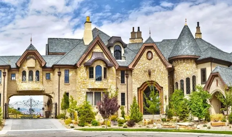 20 Stone Mansion Ideas for Classic & Modern Designs 8 A storybook stone mansion with multiple turrets, copper accents, and a porte-cochère leading to an iron gate.