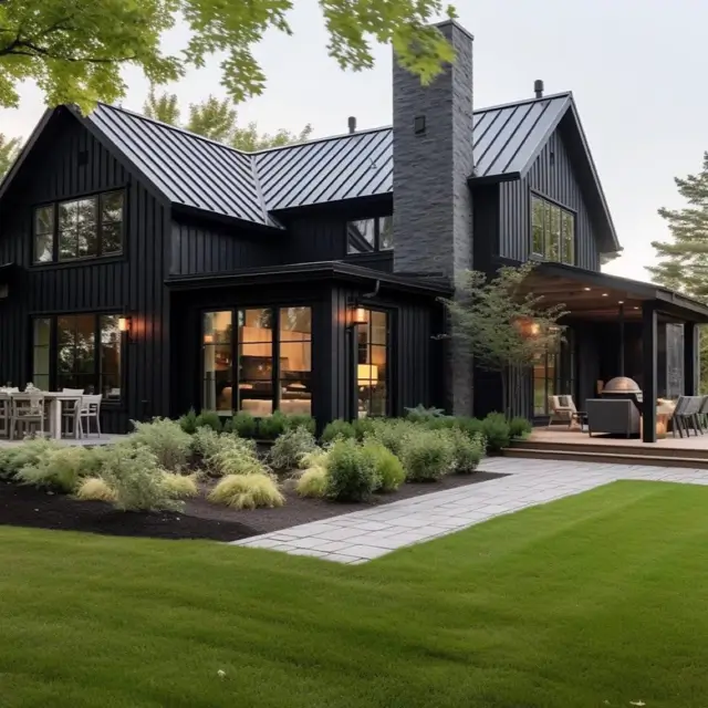 A modern black house design anchored by a prominent slate chimney, adding texture and a strong focal point.
