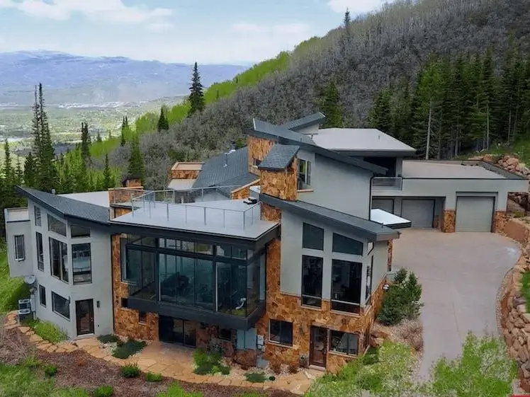 16 Mountain Mansions That Define Luxury Alpine Living 12 A modern mountain home showcasing a dynamic and complex roofline with multiple angles, blending stone and stucco siding.