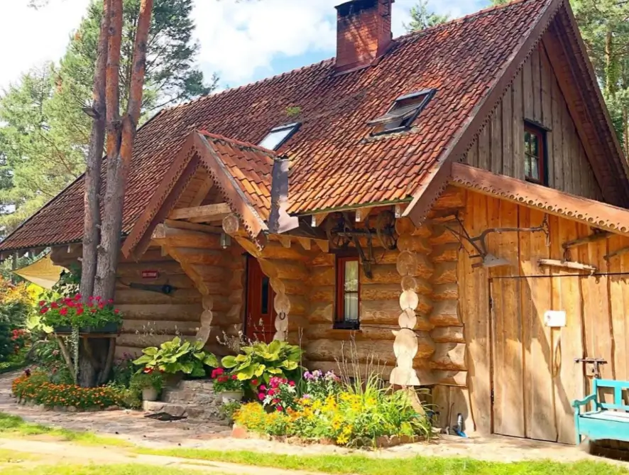 60 Charming Small Log Cabin Ideas to Inspire Your Rustic Retreat 10 A small log cabin with decorative carved woodwork, a red tile roof, and a colorful flower garden.