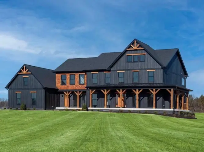 A modern black farmhouse exterior contrasted with warm, rustic timber posts on a wraparound porch.