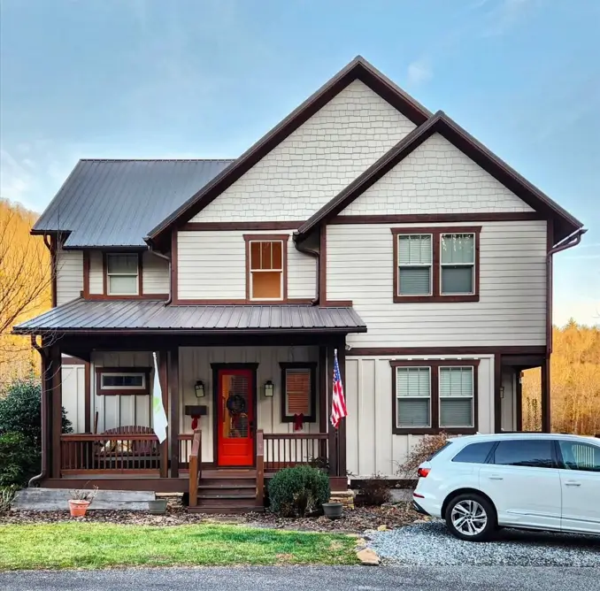 A modern craftsman house exterior featuring off-white siding, dark brown trim, a metal roof, and a bright red front door.