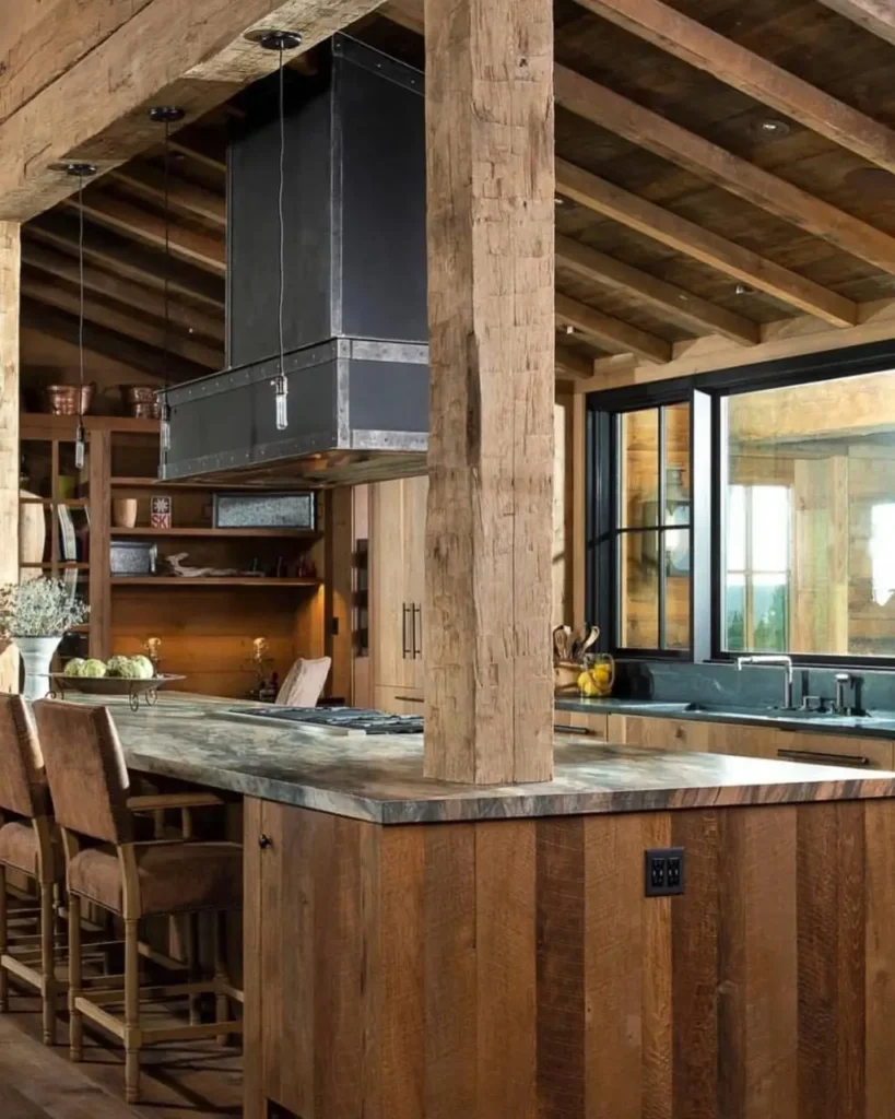 A modern rustic kitchen featuring a statement industrial range hood over a reclaimed wood island with leather bar stools.