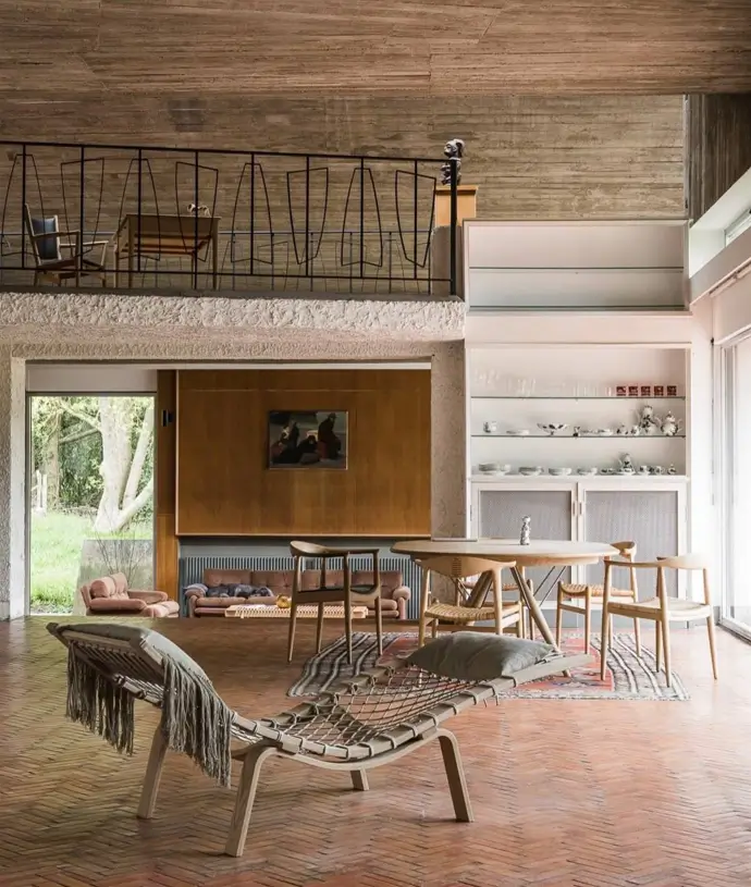A warm and inviting Brutalist interior featuring exposed concrete walls balanced with natural wood furniture and soft, textured textiles.