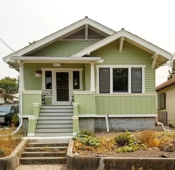 A charming craftsman bungalow with soft sage green siding, white trim, and a welcoming front porch.