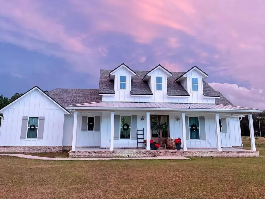An inspiring off-white farmhouse exterior with a brick porch and three dormer windows, presented as a feature image for timeless white farmhouse ideas.