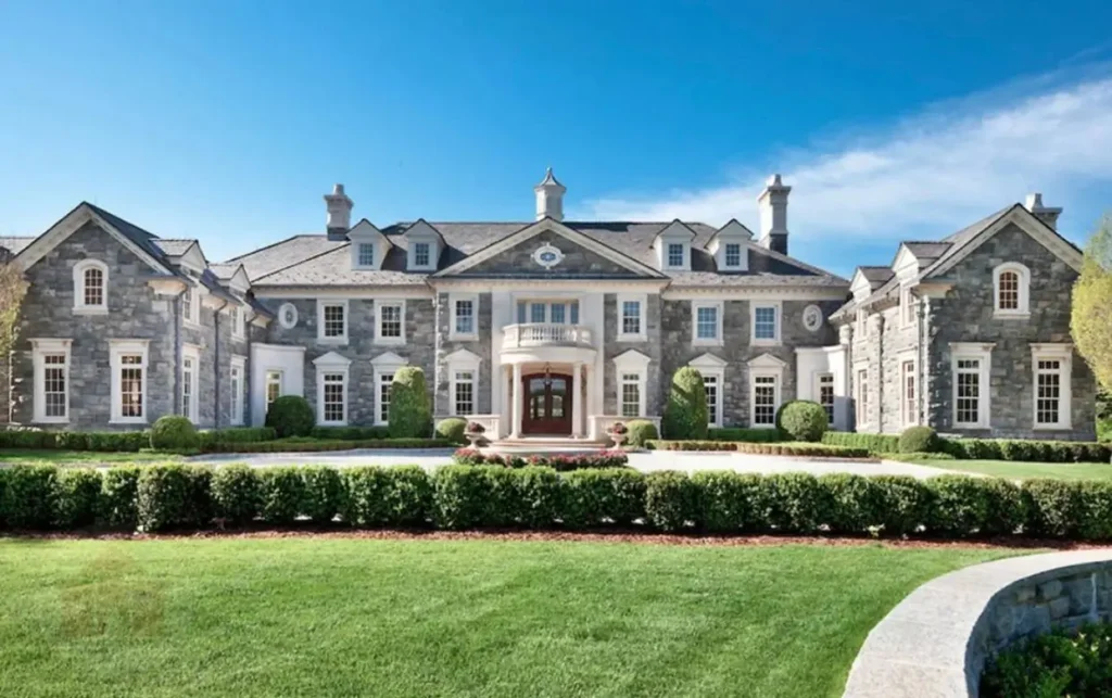 The Ultimate Guide to Luxury Mansion Design: 33 Ideas for Grandeur 3 A stately stone luxury mansion house with a symmetrical facade and circular driveway.