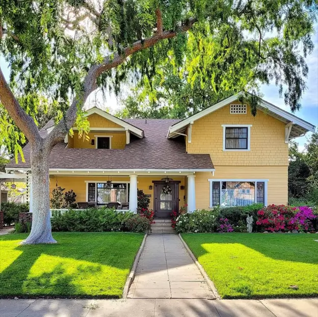 A large, sunny craftsman house with buttery yellow siding, crisp white trim, and a wide front porch.