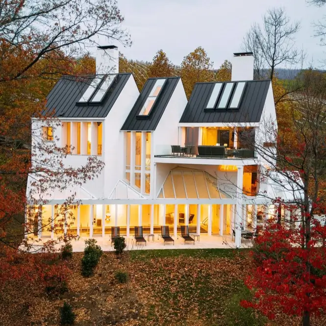 A stunning house design with multiple white gables and a black metal roof, set within a Virginia vineyard in late fall.