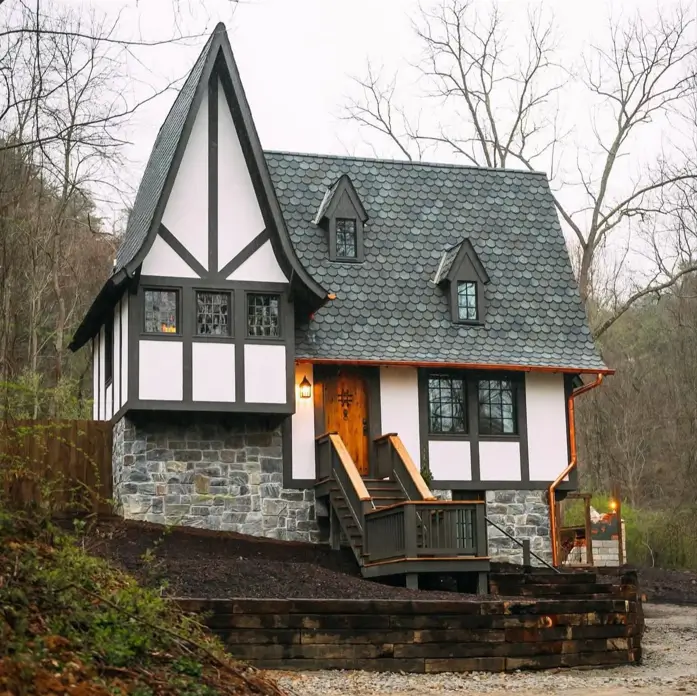 A unique house design featuring a storybook Tudor cottage with a stone base, half-timbering, and a steep scalloped roof.