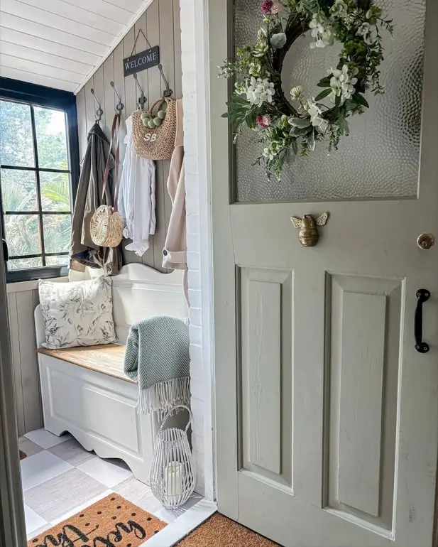 Modern farmhouse mudroom with a white storage bench, black hooks, and vertical wall paneling.
