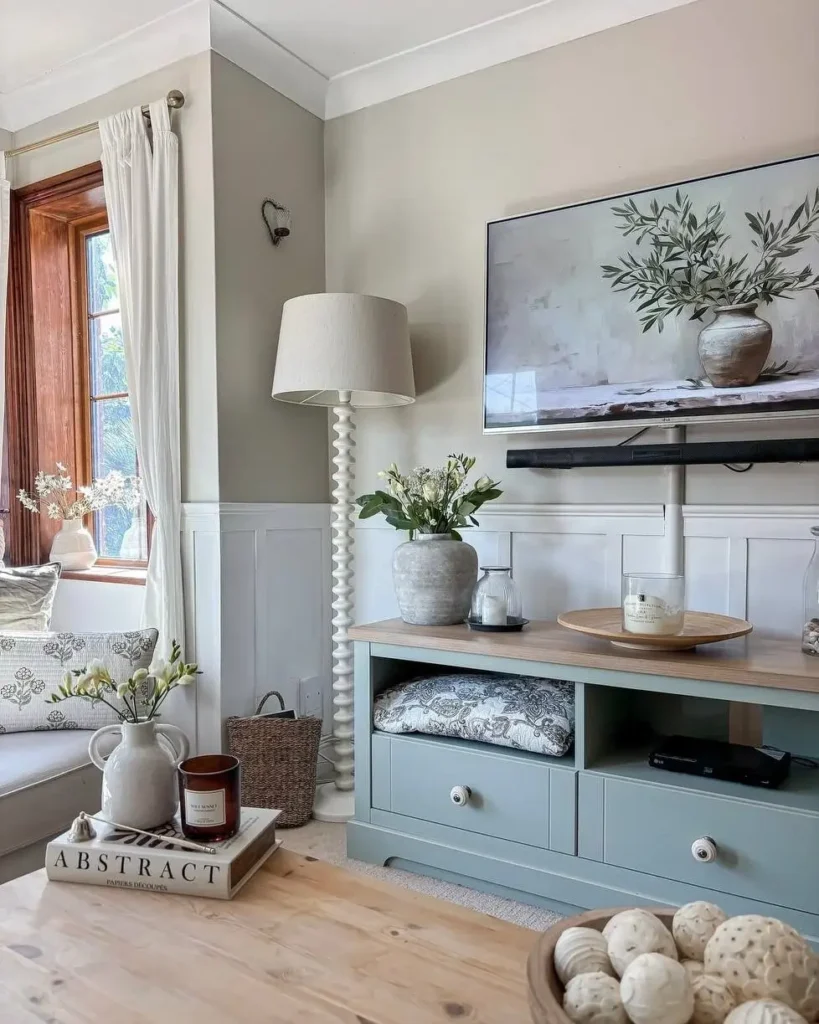 Modern farmhouse living room with a sage green media console, board and batten walls, and a large TV displaying art.