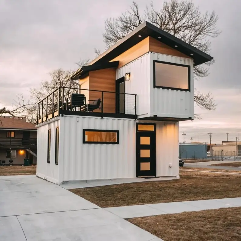 A modern two-story small container home with a white base, a wood-clad upper level, and a second-floor balcony.