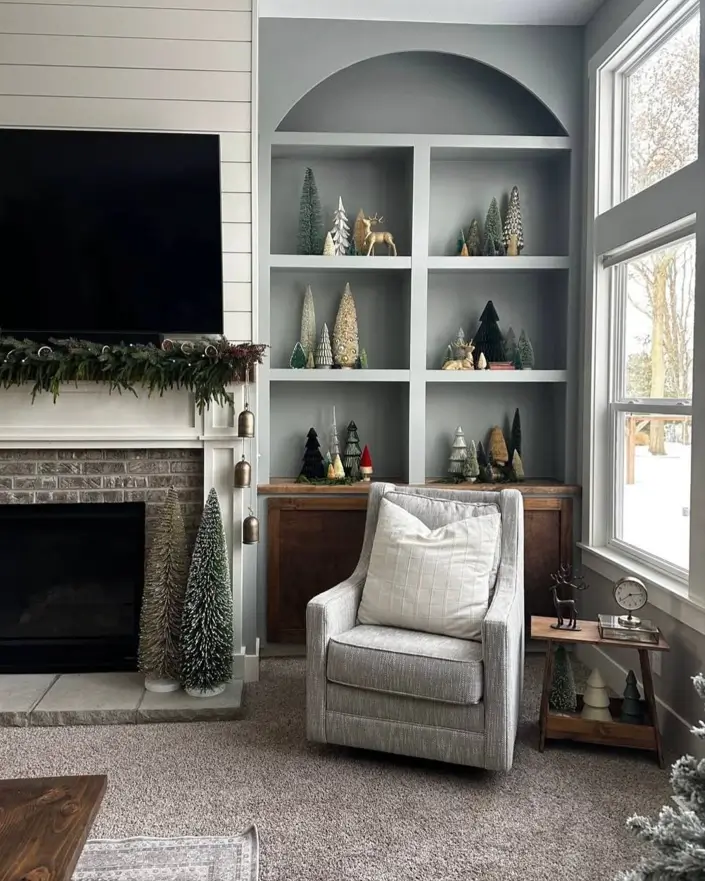 Modern farmhouse living room with gray arched built-in shelving next to a shiplap and brick fireplace.