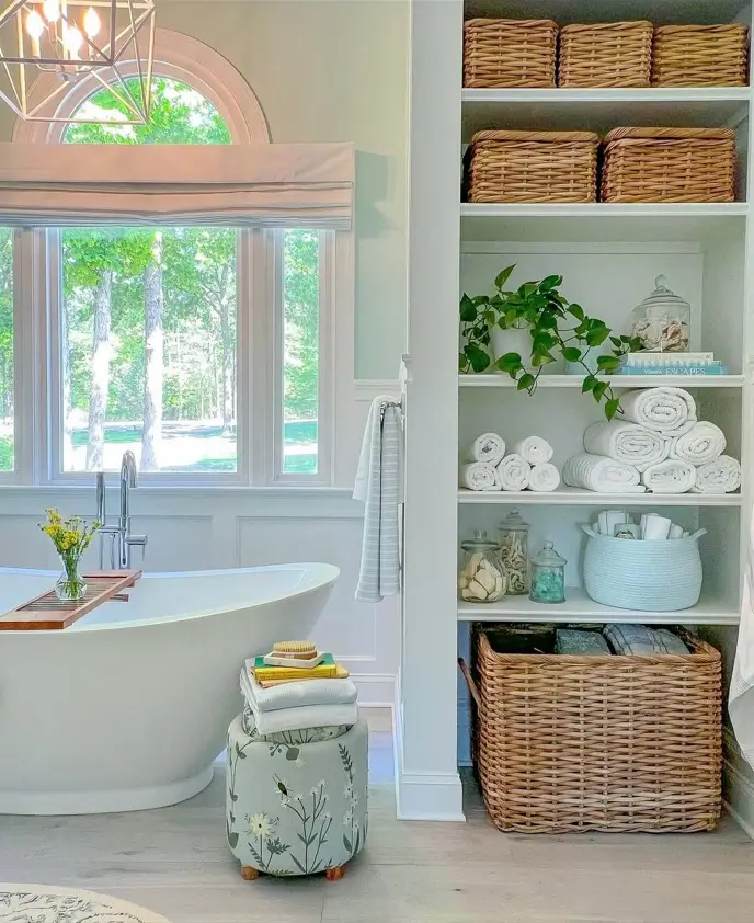 Modern farmhouse bathroom with built-in shelves, large wicker storage baskets, and a white freestanding tub.