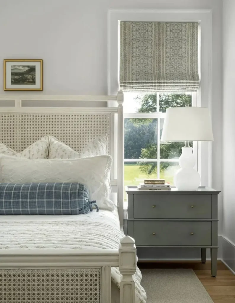 Modern farmhouse bedroom with a caned headboard, gray nightstand, and a blue plaid pillow.