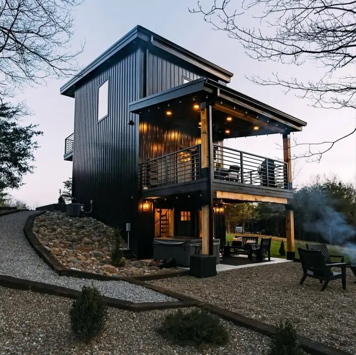 A beautiful modern house design featuring a three-story black tower with a patio on each level at twilight.