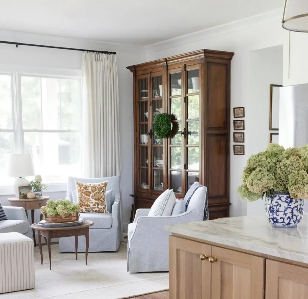 Modern farmhouse living room featuring a large dark wood display cabinet and light blue armchairs.