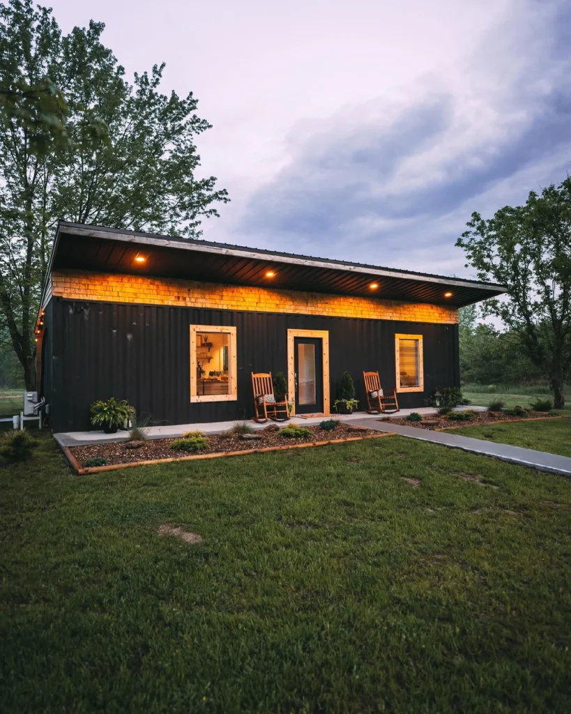 Dark-colored single-story shipping container home with a sloped roof.