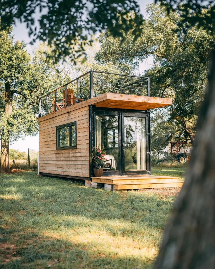 Single shipping container home with wood siding and a rooftop deck.